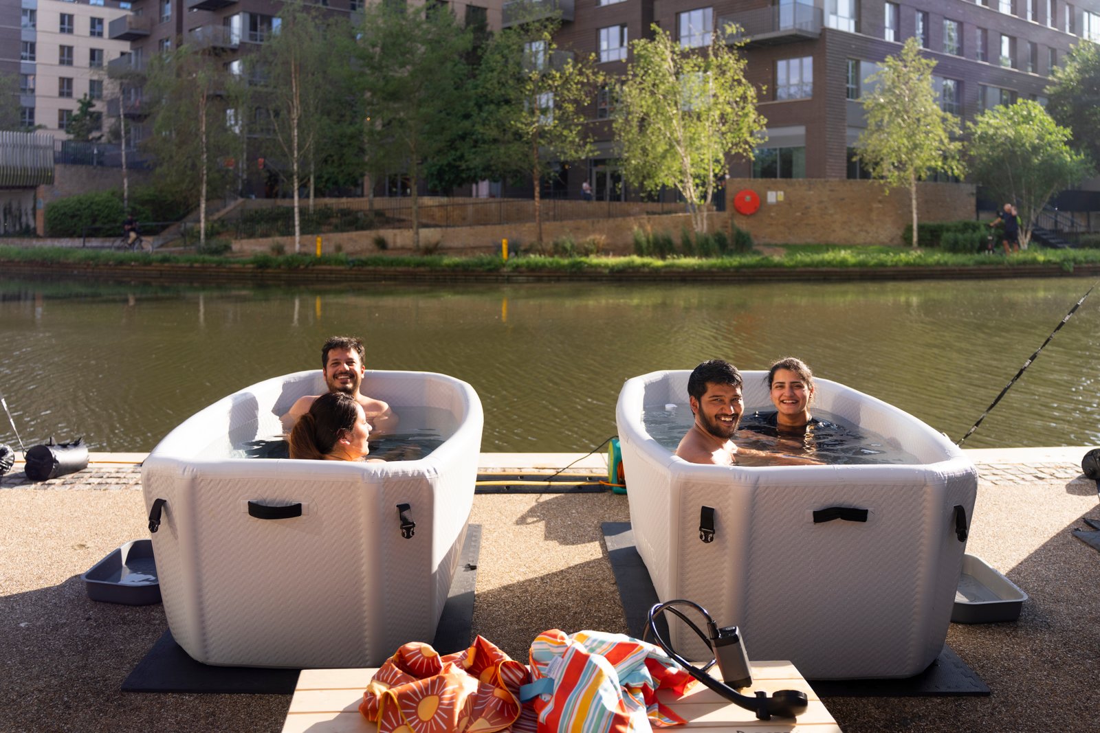 Group of friends laughing together in cold plunge baths at a SMÜG community event