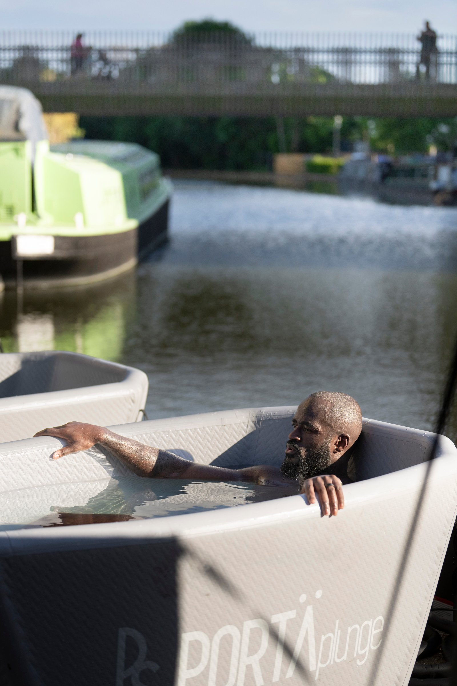Man immersed in a cold plunge bath by a canal